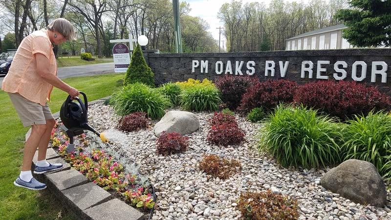 Kathy watering flowers at rv resort entrance