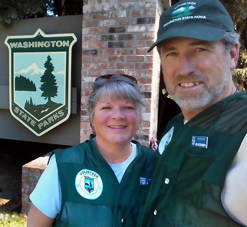 Washington State Park Volunteers, Workampers Jon & Sherry Hockersmith smiling in front of Washington State Parks sign.