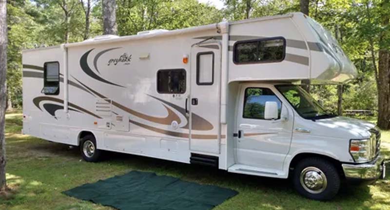 Workampers Don and Pat Hawes, Class C RV parked in at a campground, wooded area
