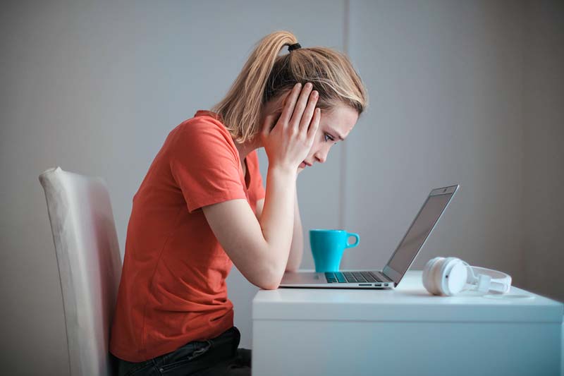 Frustrated woman looking at laptop while struggling with Facebook job searches.