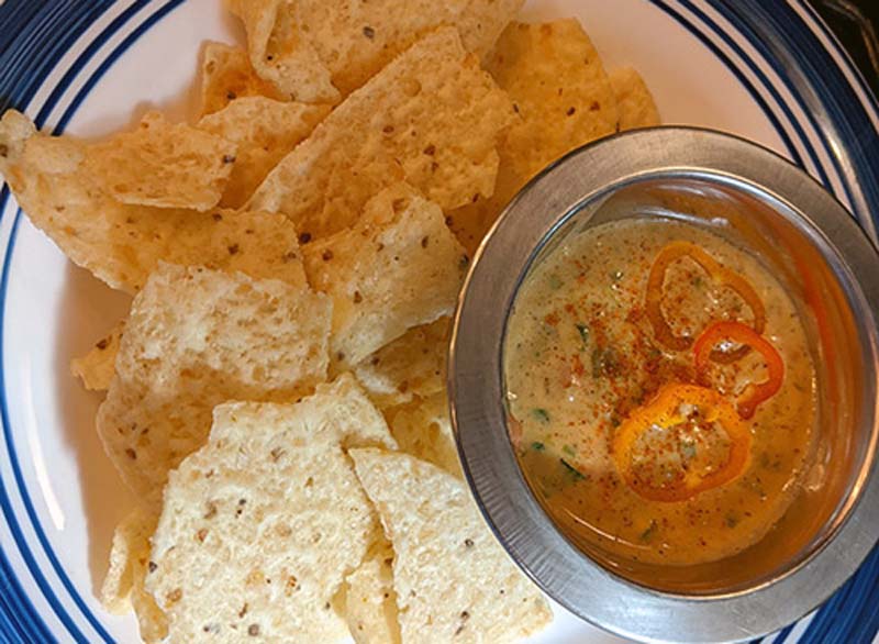 Plate with chips and a bowl of homeade Arkansas Cheese Dip.