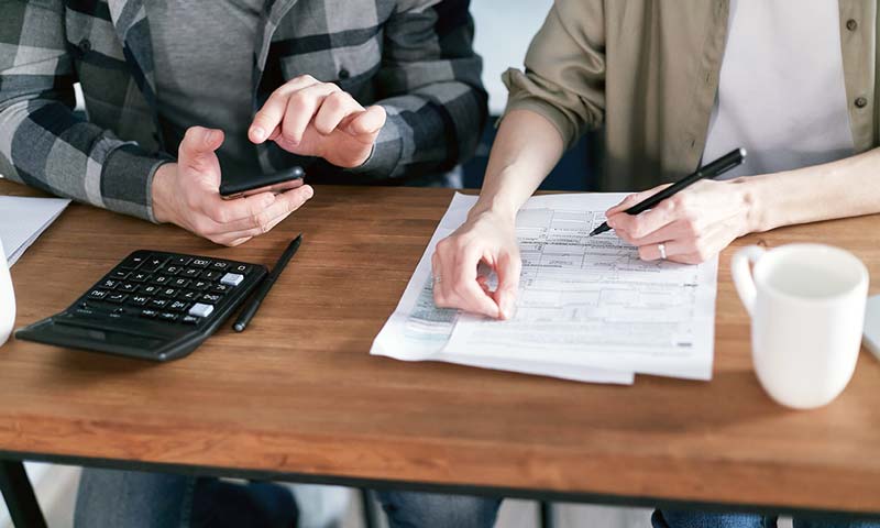 Workamping couple completing taxes at home, organizing documents and forms on a table.