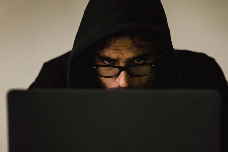Man in a hoodie concentrating at a computer, representing researching or spotting Workamper scams.