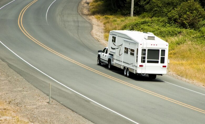 Pickup truck towing a 5th wheel trailer on the highway.