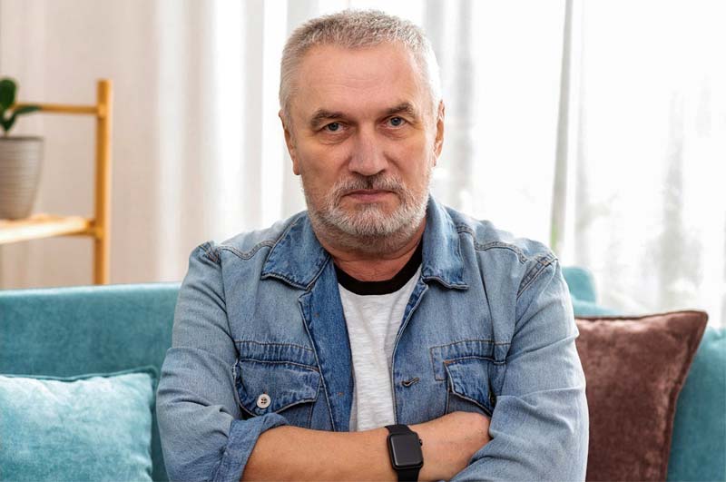 Frustrated man sitting on a couch, arms crossed, appearing upset or contemplative.