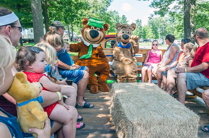 Kids and parents enjoying a hayride with Yogi Bear at Warrens Jellystone Waterpark in Wisconsin.
