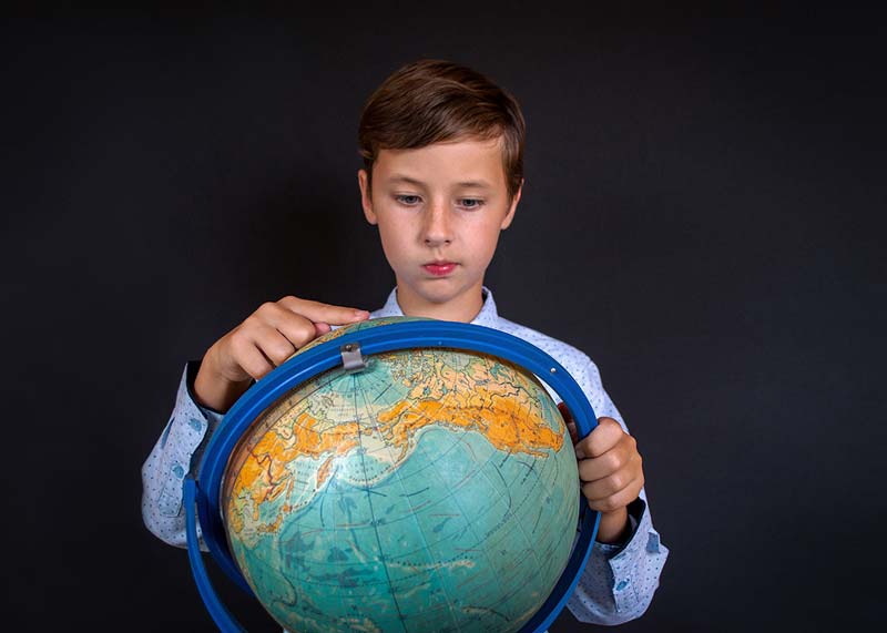 Child pointing at a globe, illustrating the process of choosing a location or domicile for RV life.