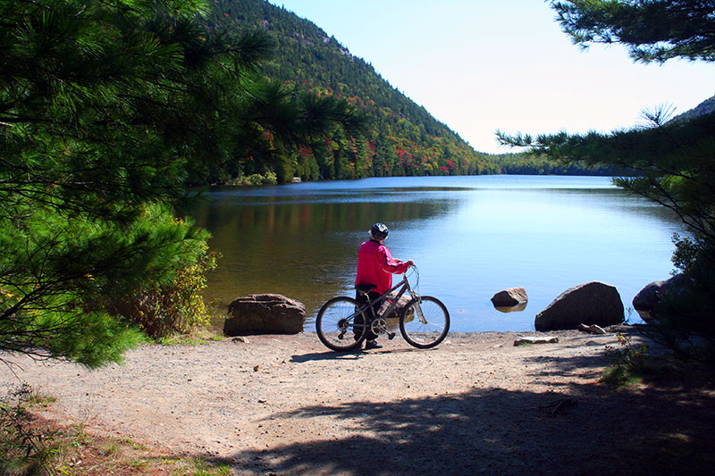 Woman standing with bike looking at lake in Acadia National Park