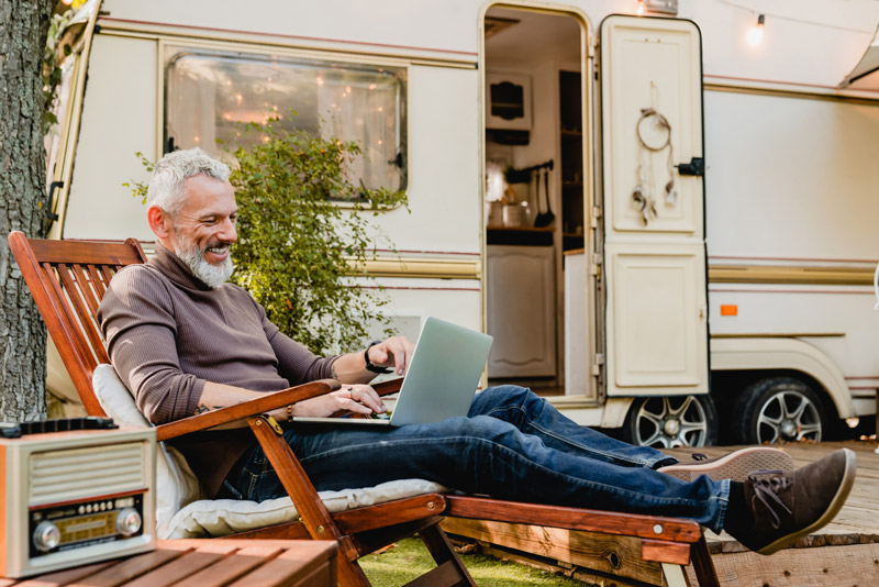 man working on laptop outside an rv