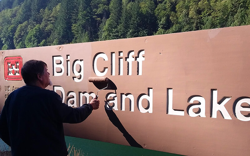 ralph hess painting a sign at big cliff usace willamette valley project