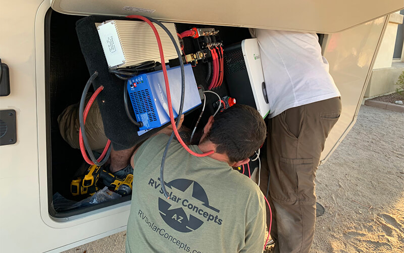 rv solar concepts crew positioning a preassembled control panel into an rv compartment
