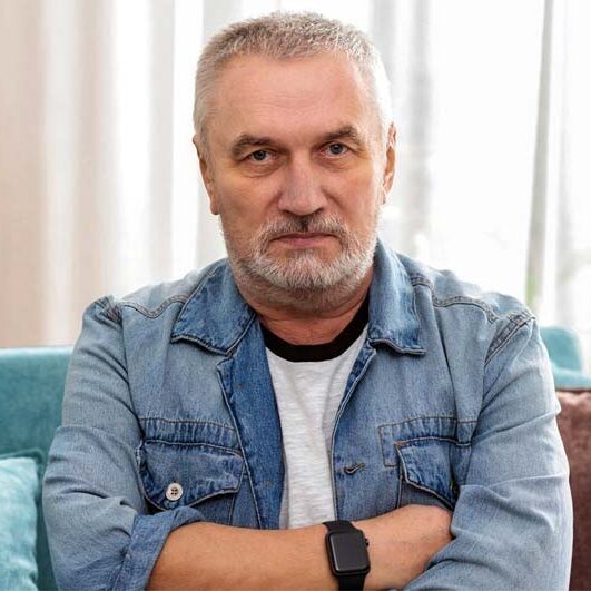 Frustrated man sitting on a couch, arms crossed, appearing upset or contemplative.