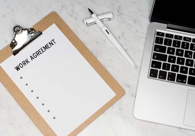 Work agreement on a clipboard beside a laptop, showing documentation and planning for Workampers before accepting a job.