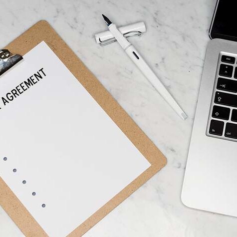 Work agreement on a clipboard beside a laptop, showing documentation and planning for Workampers before accepting a job.