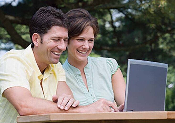 Couple working on a laptop outside, using an online job search tool to find Workamping positions.