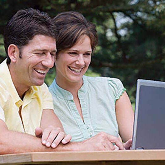 Couple working on a laptop outside, using an online job search tool to find Workamping positions.