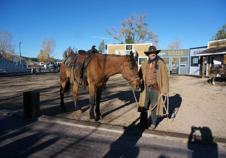 Actor – Train Robber & Cowboy standing next to horse in old western looking stage.