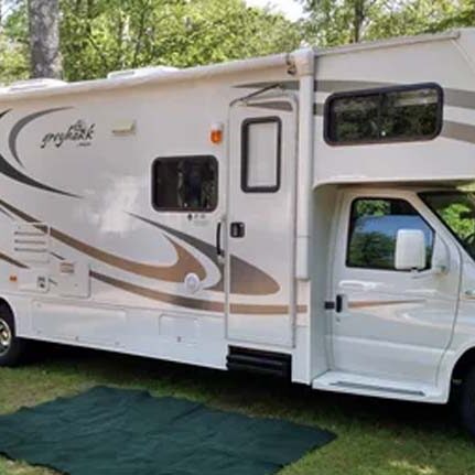 Workampers Don and Pat Hawes, Class C RV parked in at a campground, wooded area