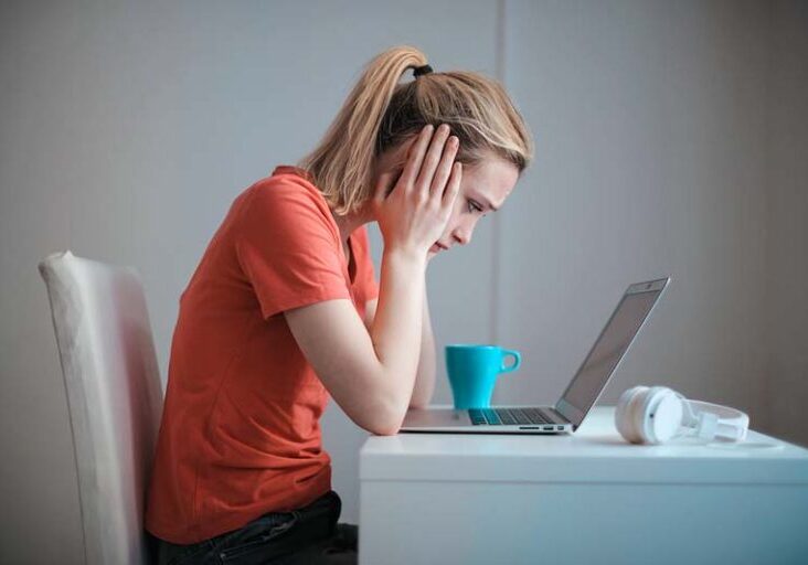Frustrated woman looking at laptop while struggling with Facebook job searches.