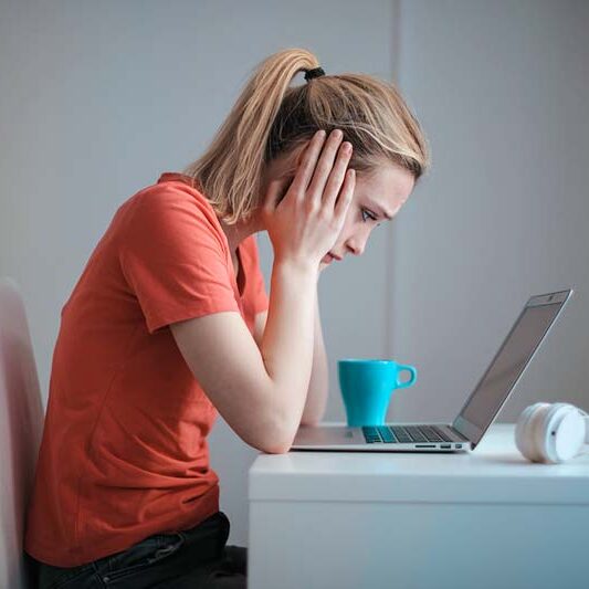 Frustrated woman looking at laptop while struggling with Facebook job searches.