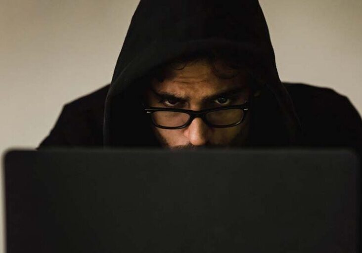 Man in a hoodie concentrating at a computer, representing researching or spotting Workamper scams.
