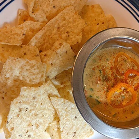 Plate with chips and a bowl of homeade Arkansas Cheese Dip.