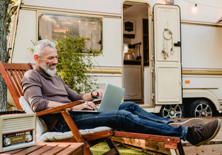 man working on laptop outside an rv