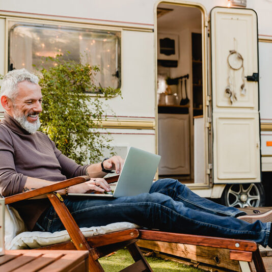 man working on laptop outside an rv