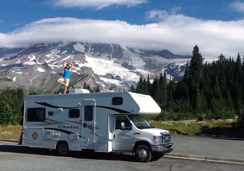 Solo Workamper Kristy Halliday standing ontop of RV in front of Mt Rainier.