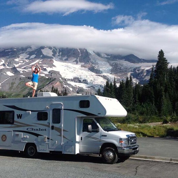 Solo Workamper Kristy Halliday standing ontop of RV in front of Mt Rainier.
