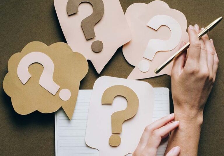 Four paper question marks with hands next to them"Questions to Ask Workamper Employers"