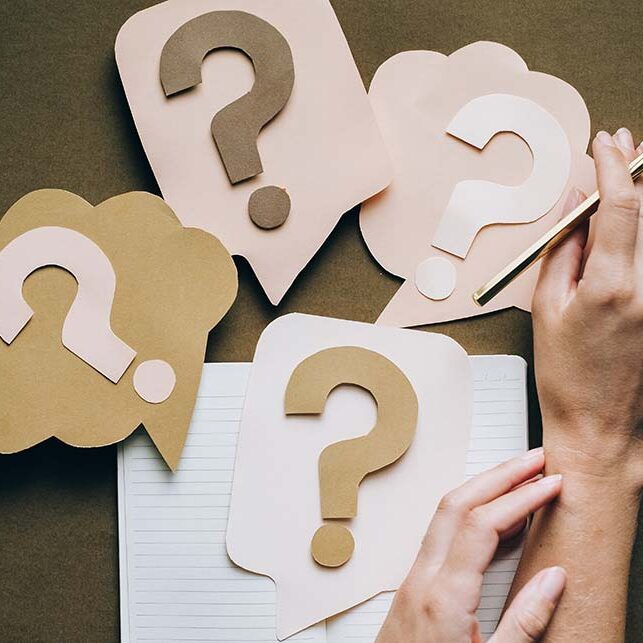 Four paper question marks with hands next to them"Questions to Ask Workamper Employers"