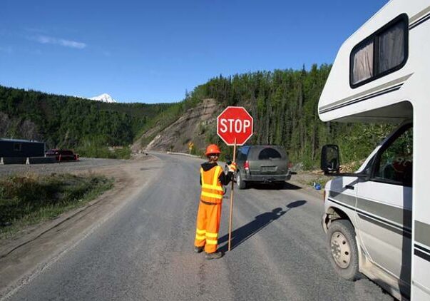 RV stopped at worker holding stop sign, road work.