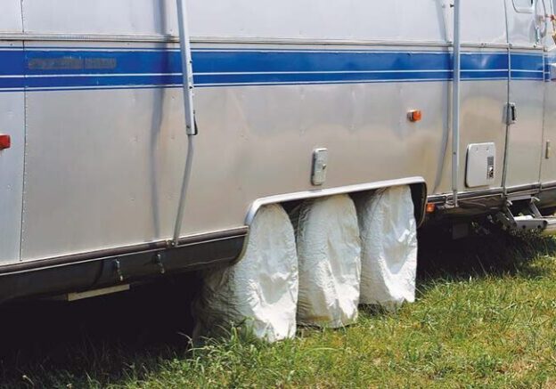 RV travel trailer with protective tire covers, illustrating proper tire care to extend lifespan and prevent damage.