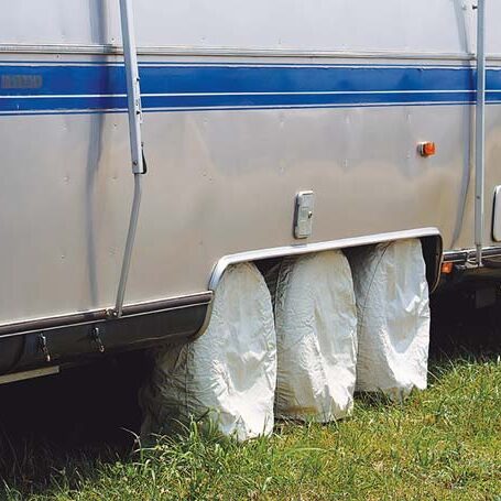 RV travel trailer with protective tire covers, illustrating proper tire care to extend lifespan and prevent damage.