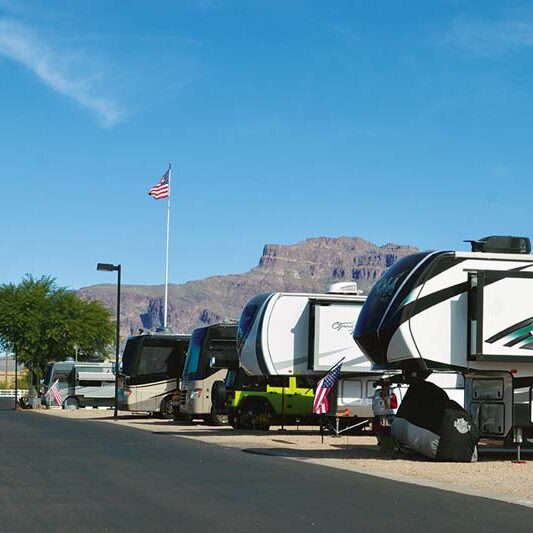 Line of RVs at Cal-Am Resort with the Superstition Mountains in the background, showcasing a popular destination for Workampers in Arizona.