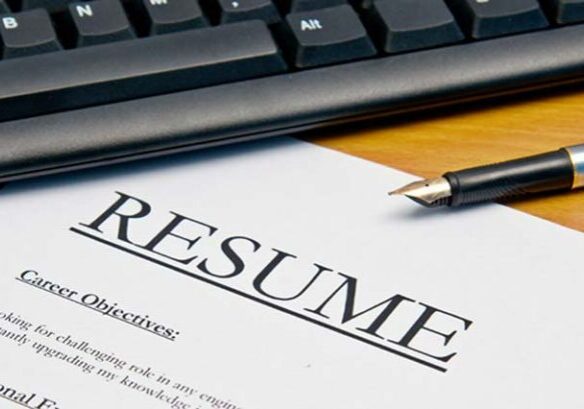 Printed resume laying on a desk next to a keyboard and pen.