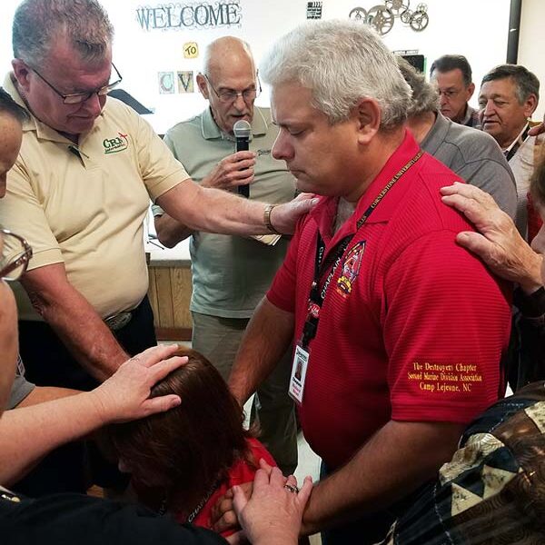 Group of people praying together, lead by Workamper Chaplain Robert N. Ruesch.
