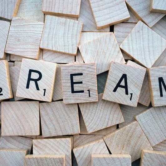 Scrabble tiles spelling out the word Dream, on top of upside down tiles.