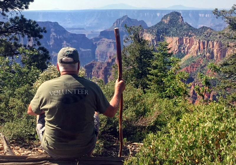 Workamper Tim Slack taking a break on a hike enjopying the view, looking out over scenic canyon landscape.