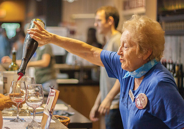 Prairie Berry staff member pouring wine into tasting glasses at the bar during a winery visit.