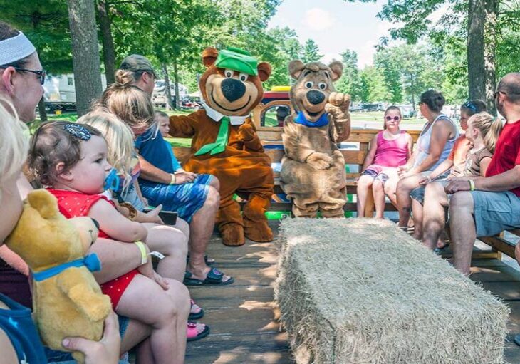 Kids and parents enjoying a hayride with Yogi Bear at Warrens Jellystone Waterpark in Wisconsin.