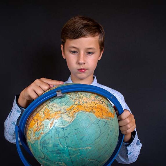 Child pointing at a globe, illustrating the process of choosing a location or domicile for RV life.