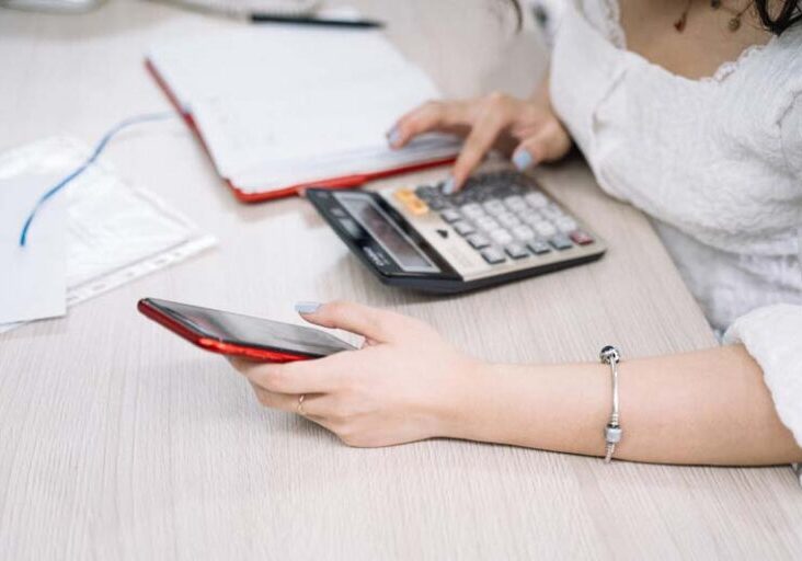 Person using calculator and phone doing the math on a Workamping job.