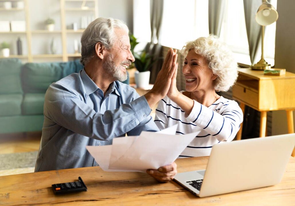 Two people celebrating with a high-five while working together on a laptop.