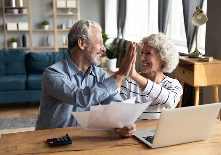 Couple high fiving in front of laptop.