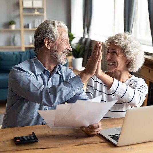 Couple high fiving in front of laptop.