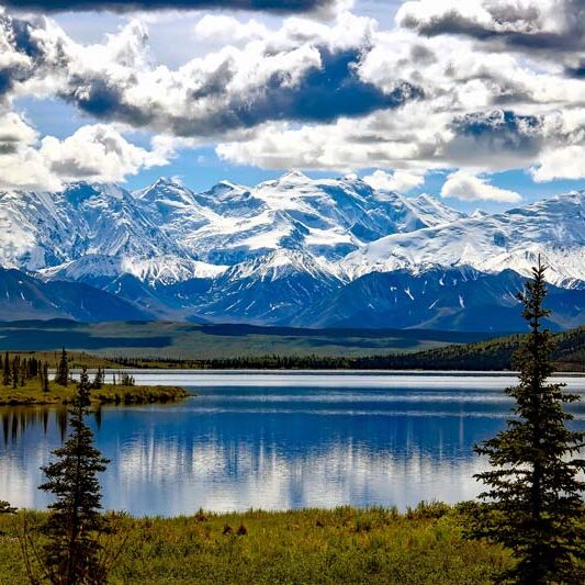Denali National Park lake view with large snow-capped mountians in the distance.