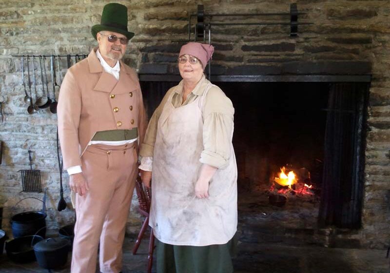 Workampers Pat and Dale Durfur pose in front of huge fire place in vintage clothing.