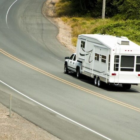 Pickup truck towing a 5th wheel trailer on the highway.